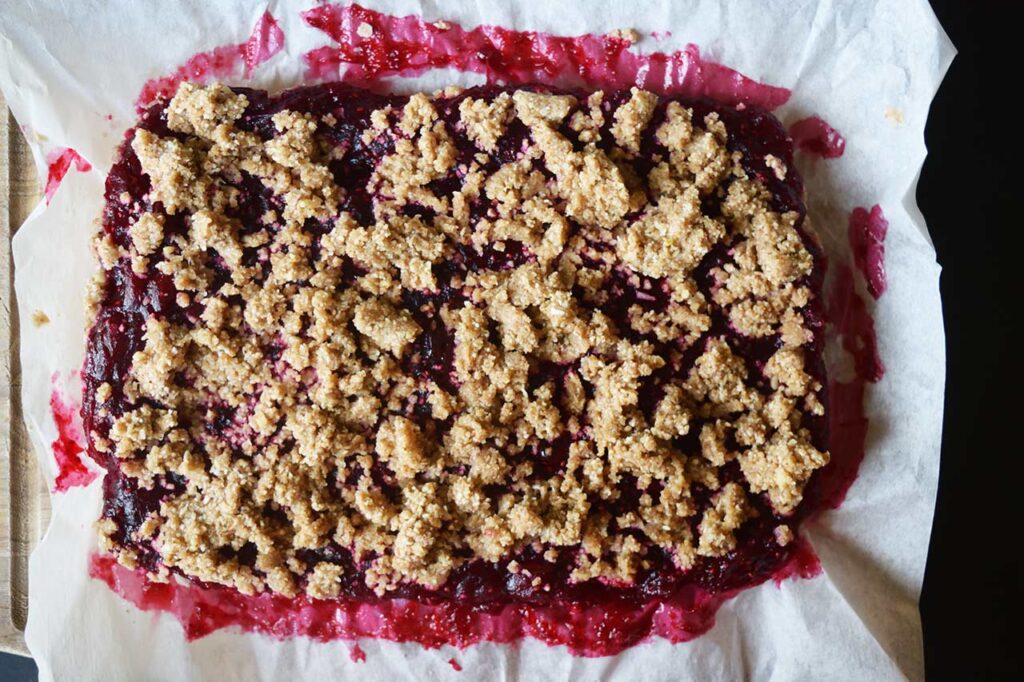 Uncut cranberry bars removed from pan and resting on parchment paper.