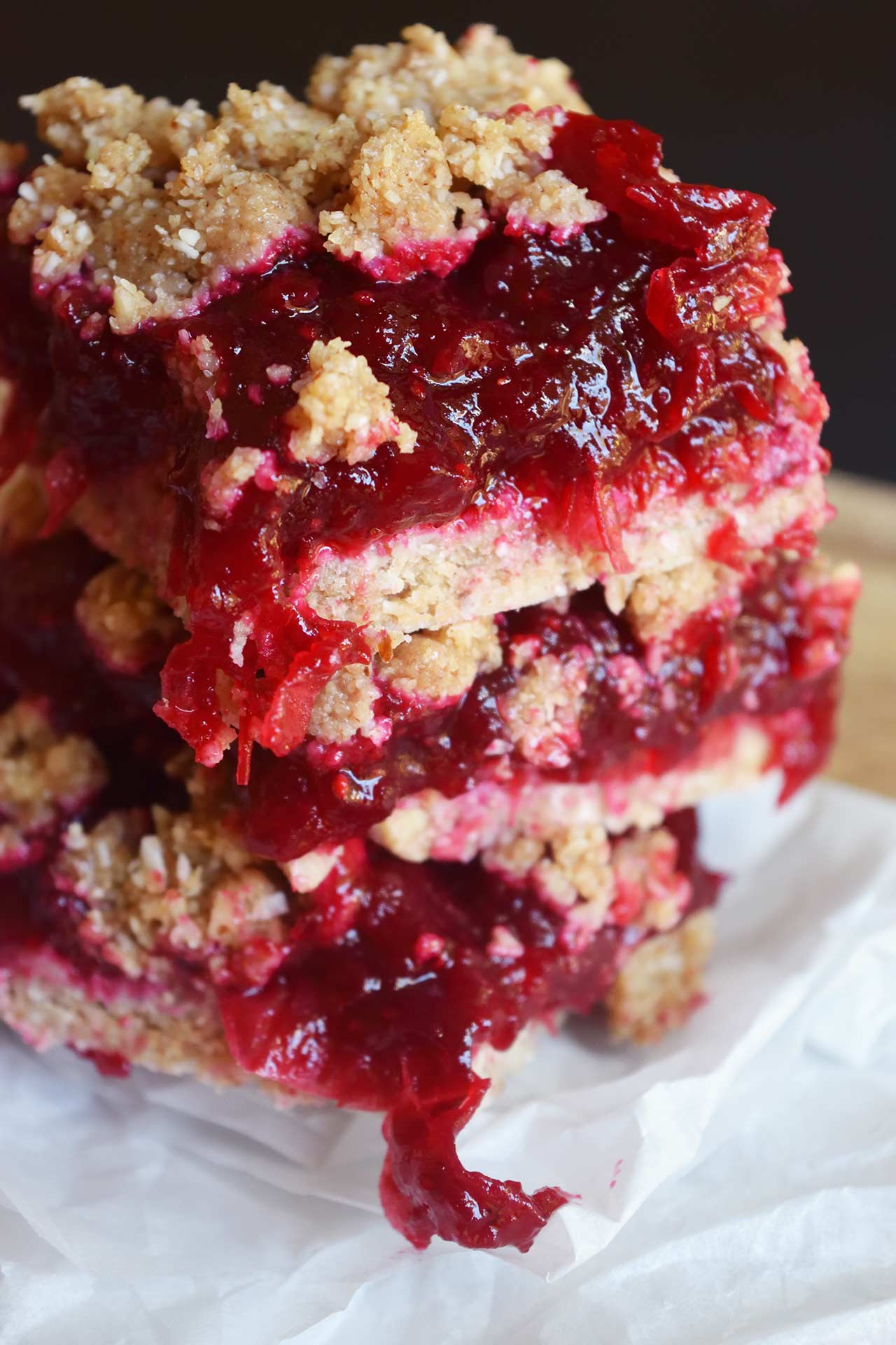 Closeup of a stack of cranberry bars sitting on parchment paper.