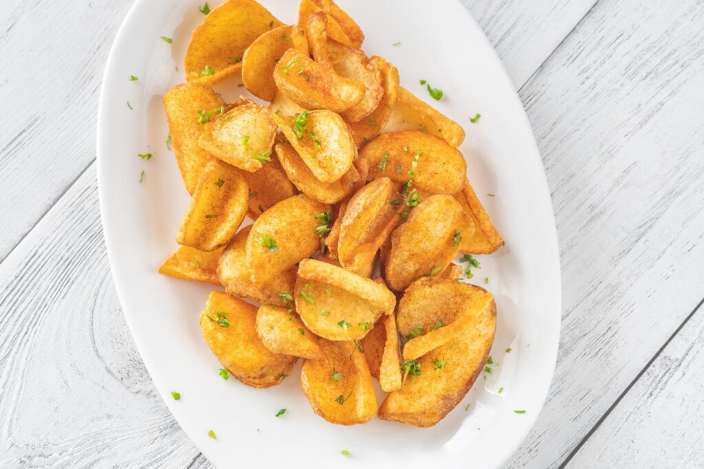 A batch of cottage fries on a white, oval platter.