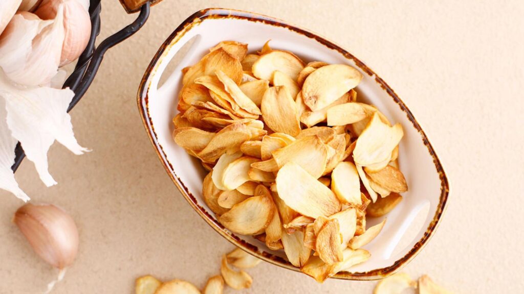 Overhead view of a ceramic bowl full of garlic chips.