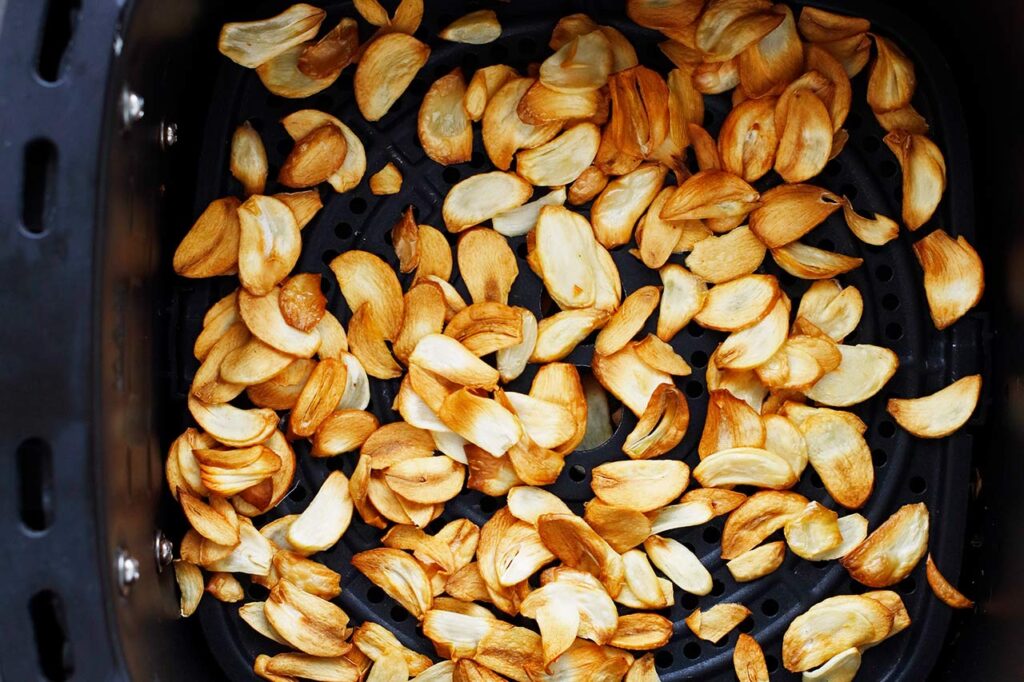 Cooked garlic chips cooling in an air fryer basket.