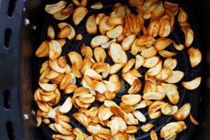 Cooked garlic chips cooling in an air fryer basket.