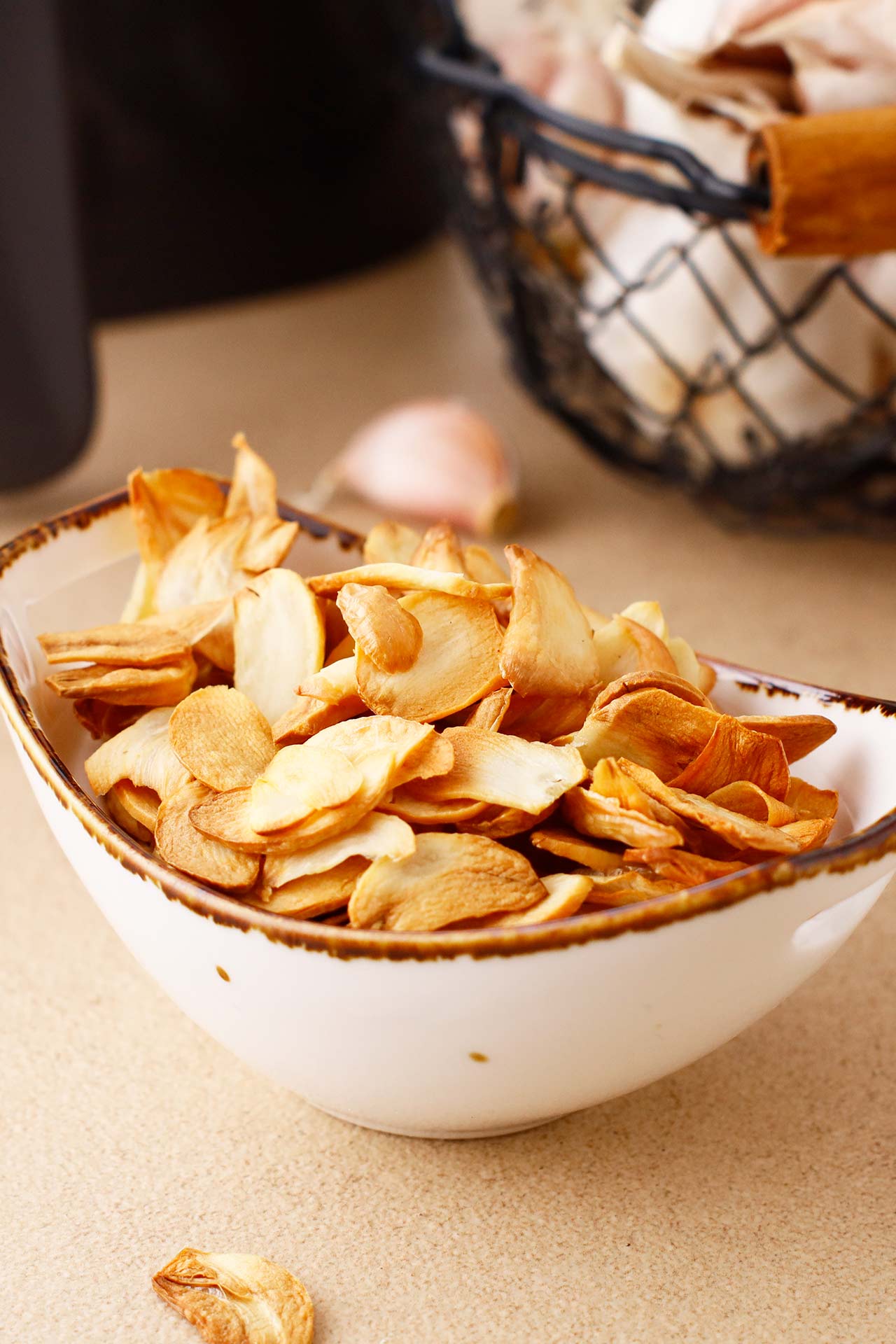 Side view of a ceramic bowl full of garlic chips.