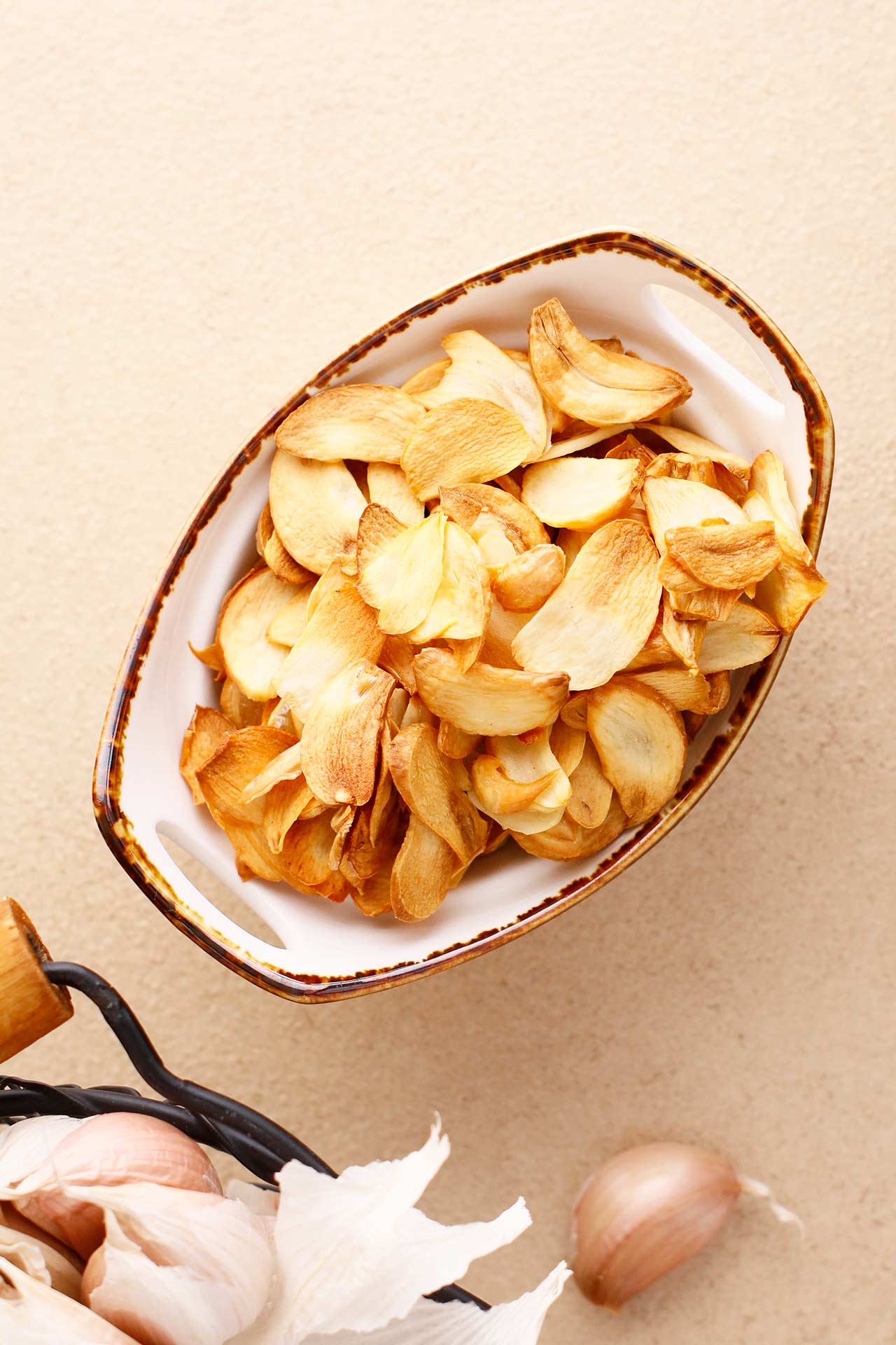 Overhead view of a ceramic bowl full of garlic chips.