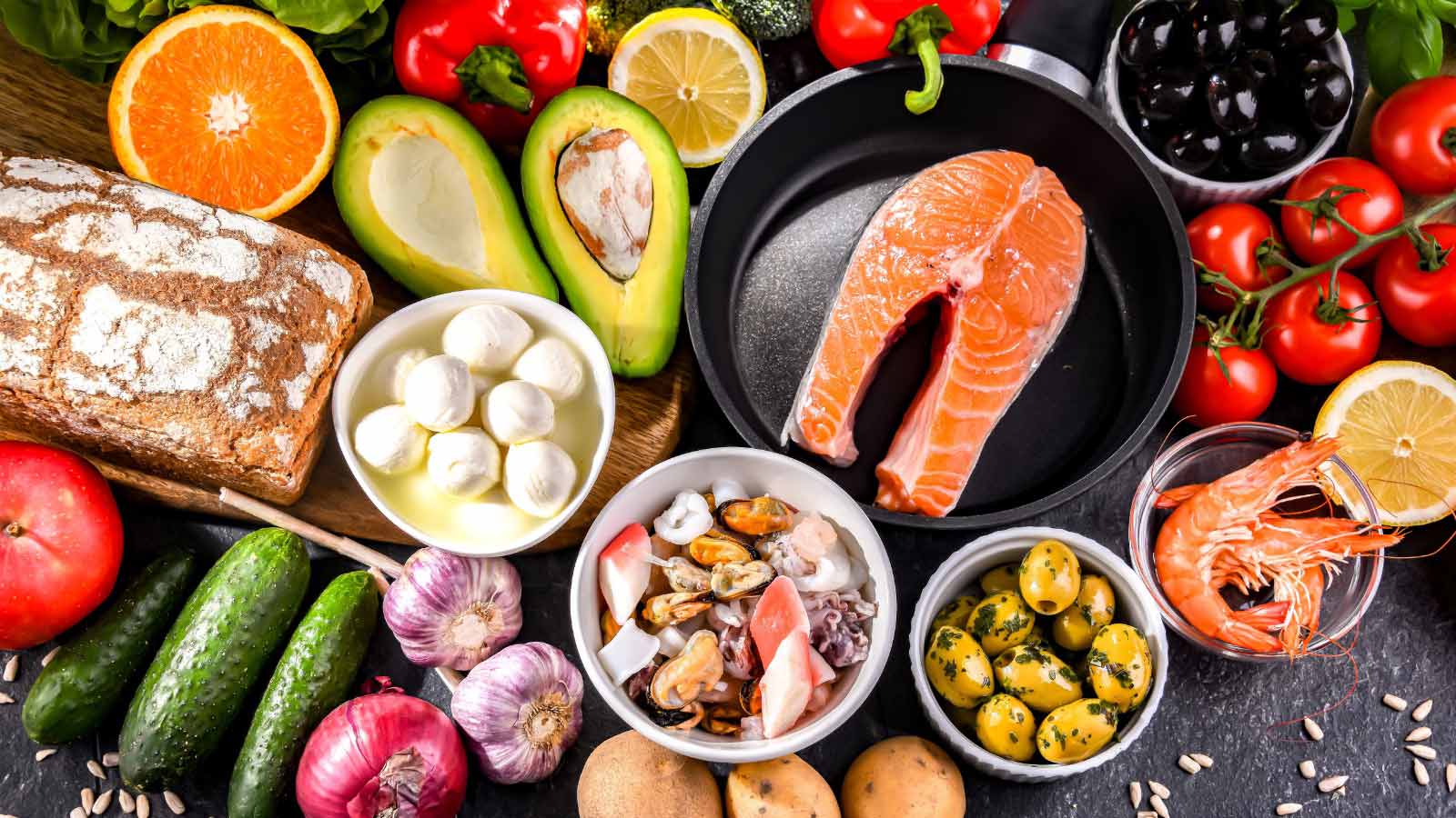 Food products representing the Mediterranean diet on a gray surface.