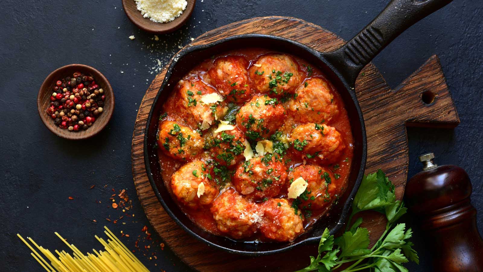 Meatballs with rice in tomato sauce in a skillet pan on dark slate, stone or concrete background.