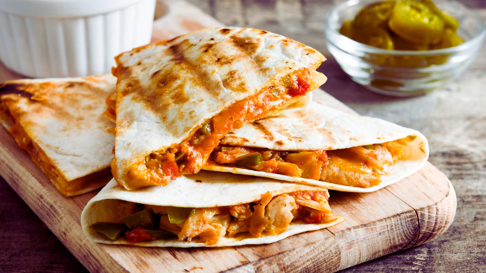 A mouthwatering image of a freshly grilled quesadilla, featuring golden, crispy edges and a gooey, melted cheese filling. This classic Mexican dish is sliced and ready to enjoy it.