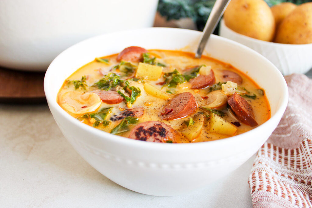 Front view of a white bowl filled with Sausage, Kale And Potato Soup.