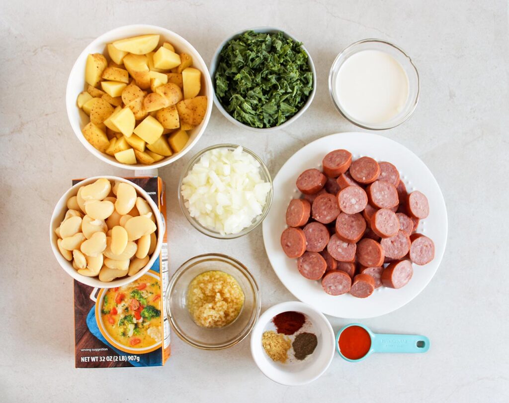Sausage, Kale And Potato Soup recipe ingredients on a white surface.