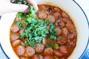 Adding kale to the bowl of soup.