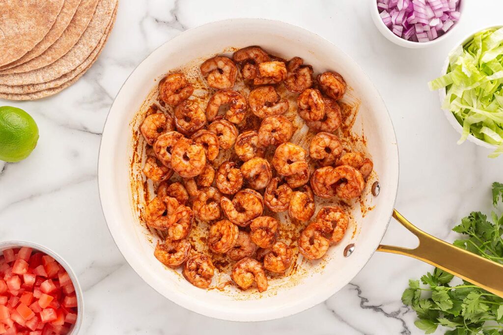 Seasoned, cooked shrimp in a skillet.