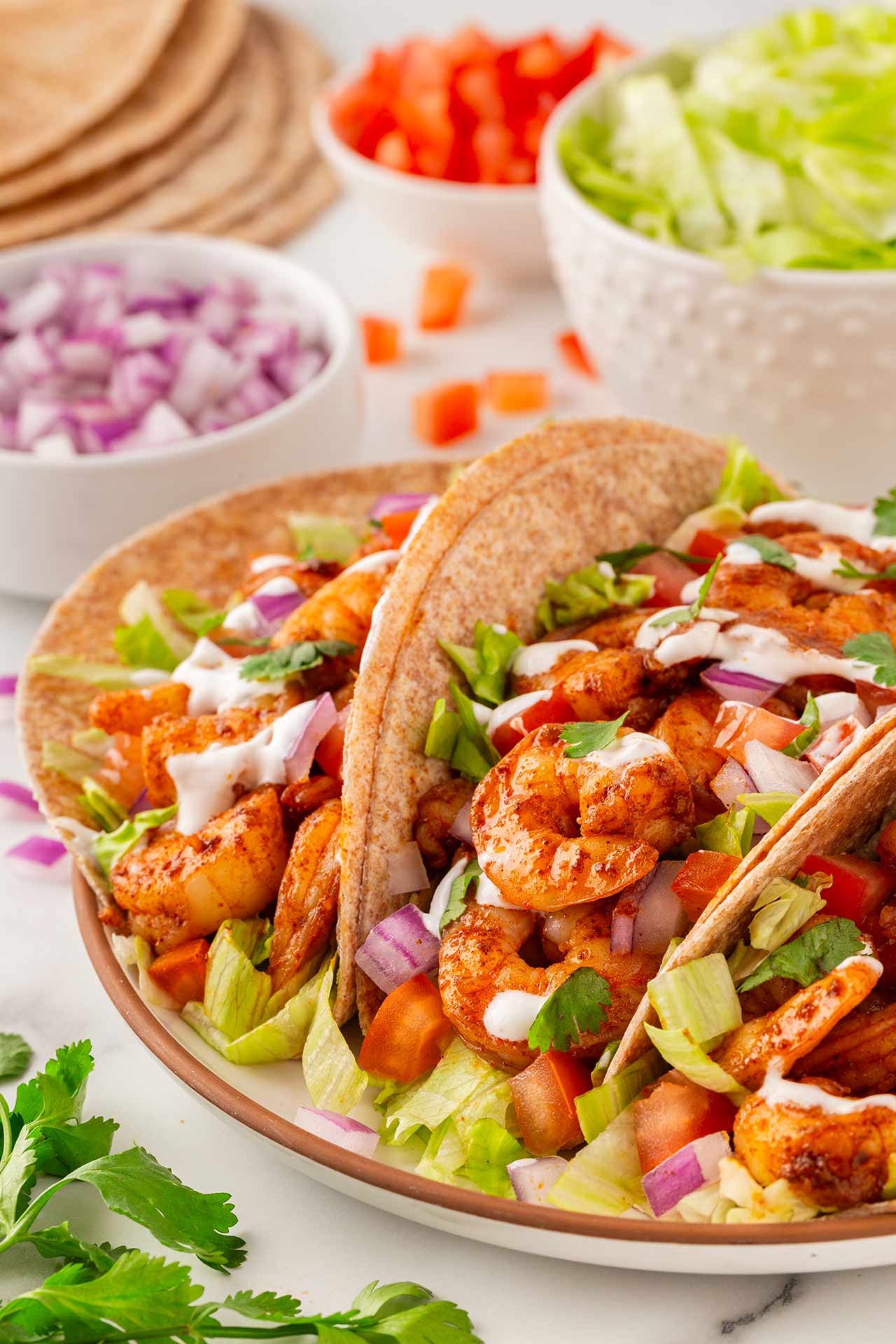 Front view of a white platter holding three shrimp tacos.