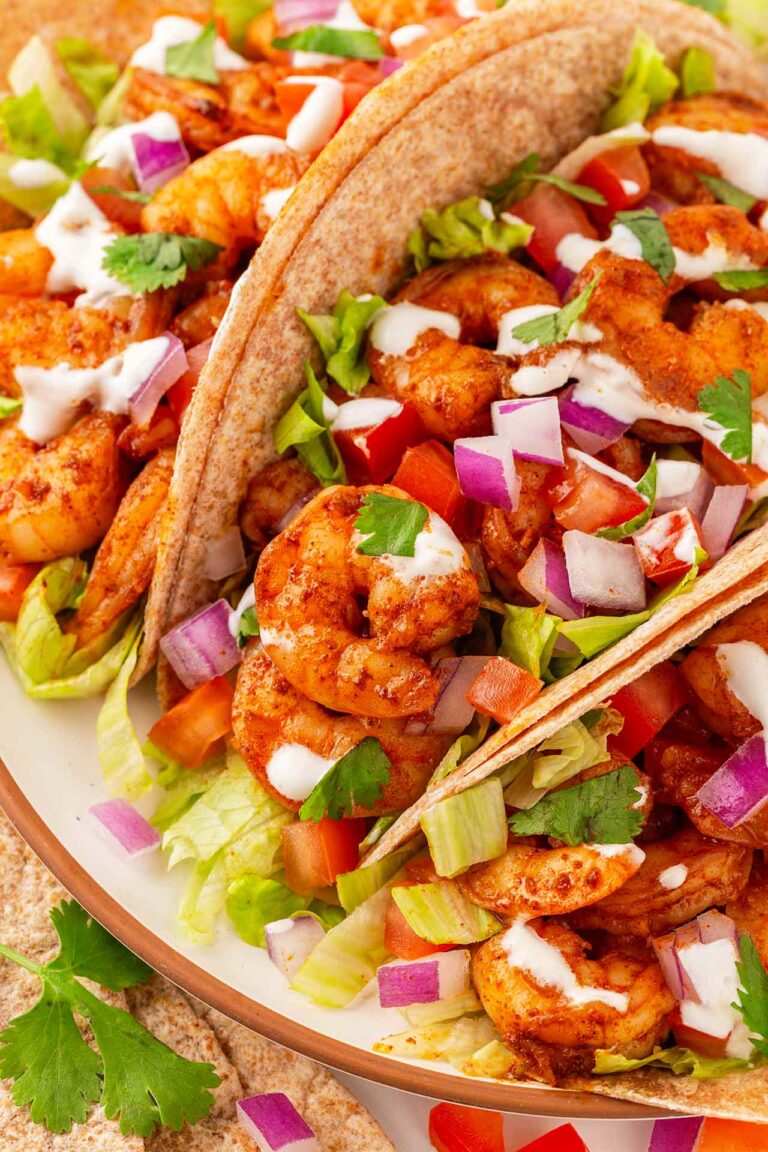 Closeup of three shrimp tacos on a platter.