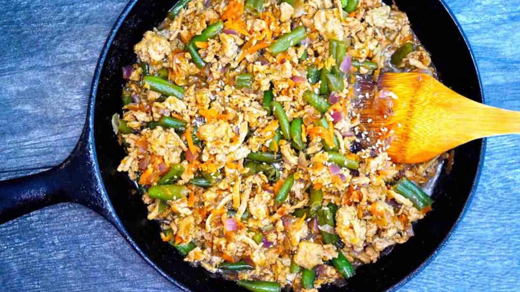 An overhead view of a cast iron skillet filled with teriyaki turkey skillet.