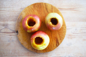 Three cored apples on a cutting board.