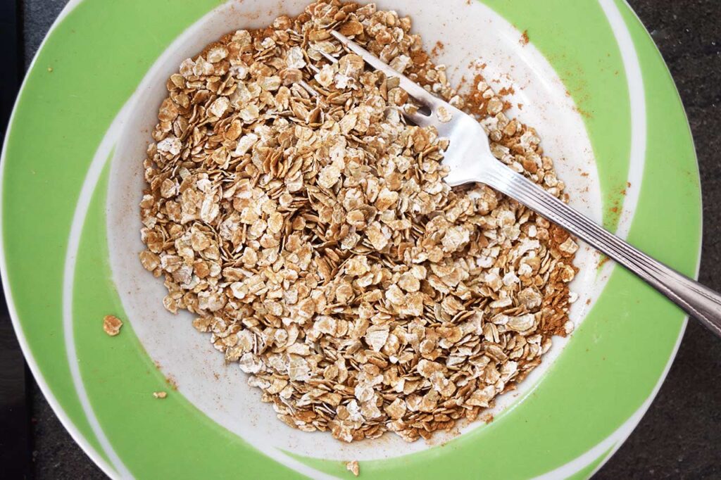 Oats mixed with spices in a mixing bowl.