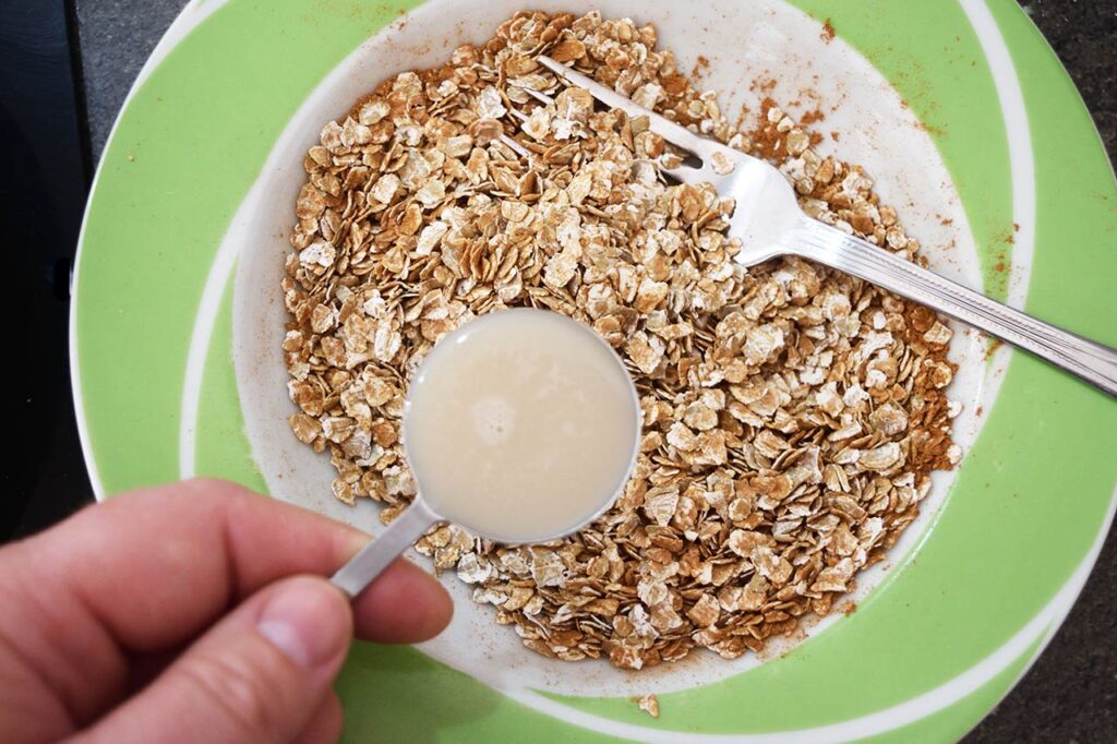 Adding milk to oats and spices in a bowl.