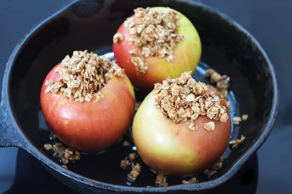 Raw, cored apples in an oiled cast iron skillet, stuffed with spiced and moistened oats.