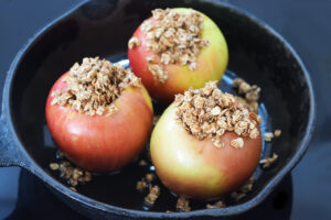 Raw, cored apples in an oiled cast iron skillet, stuffed with spiced and moistened oats.