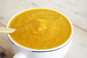 Side view of a white mug filled with Butternut Squash Soup.