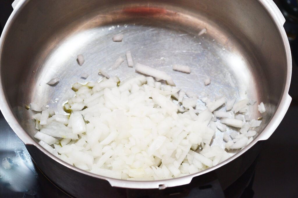 Onions added to a pot of warm oil to saut&eacute;.