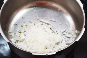 Onions added to a pot of warm oil to saut&eacute;.