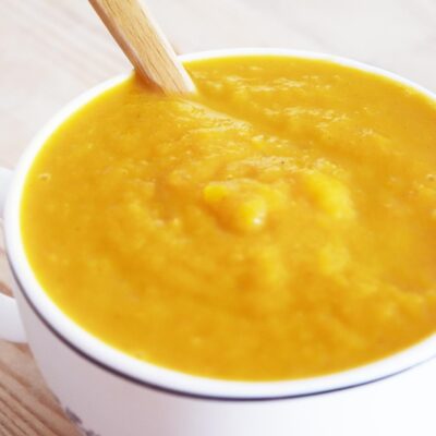Butternut Squash Soup in a white mug with a wood spoon.