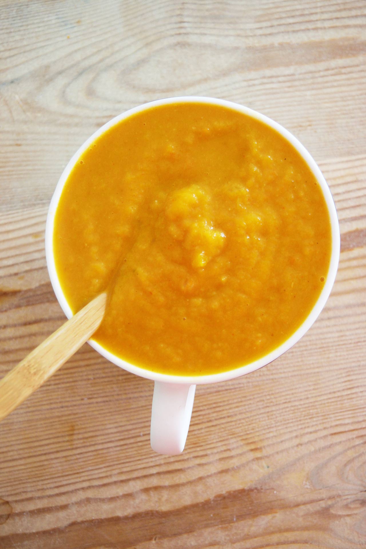 Overhead view of a white mug filled with Butternut Squash Soup.