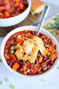 Front, partially-overhead view of a white bowl filled with Classic Chicken Chili.