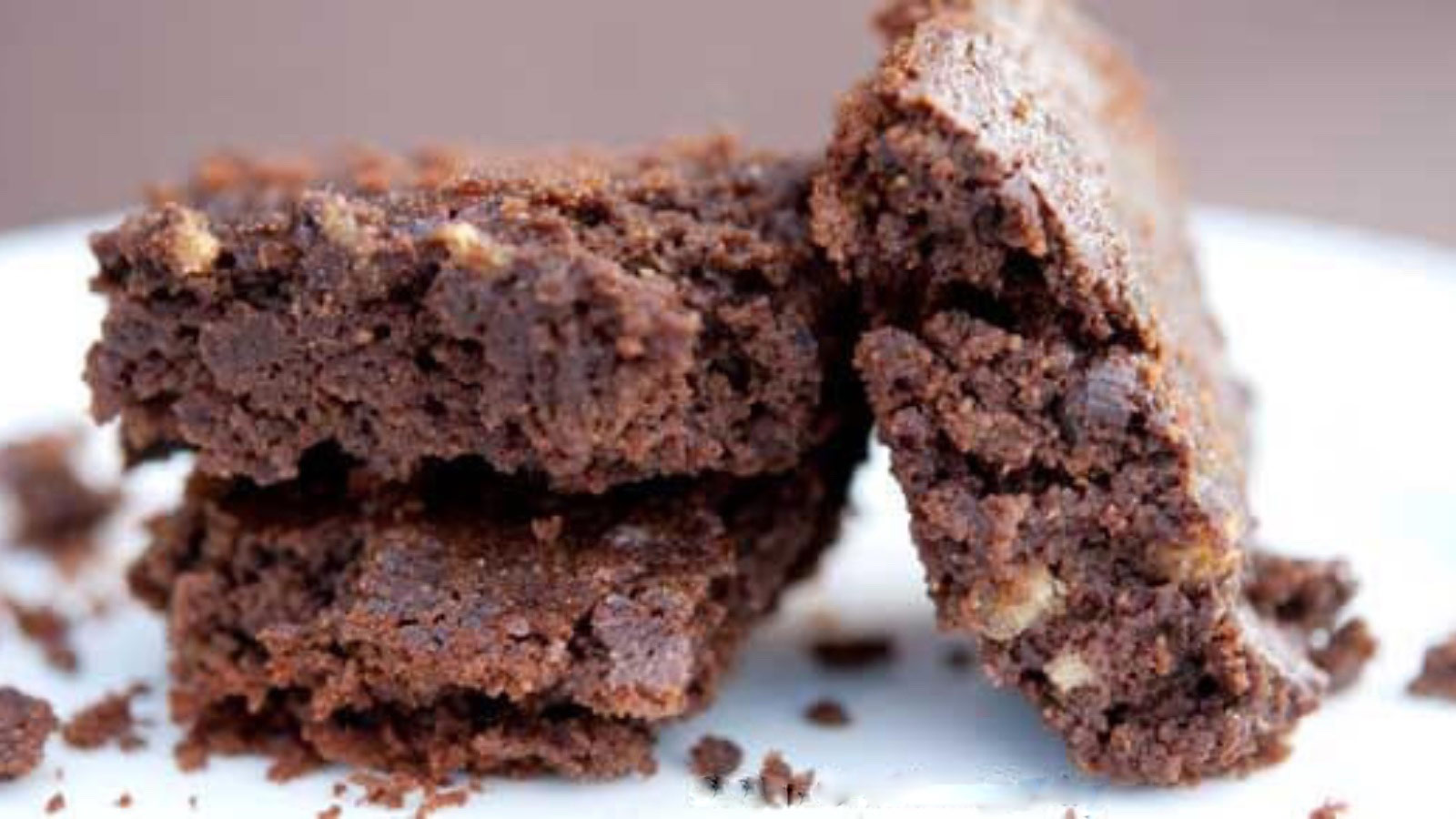 Closeup of three brownies on a white plate.