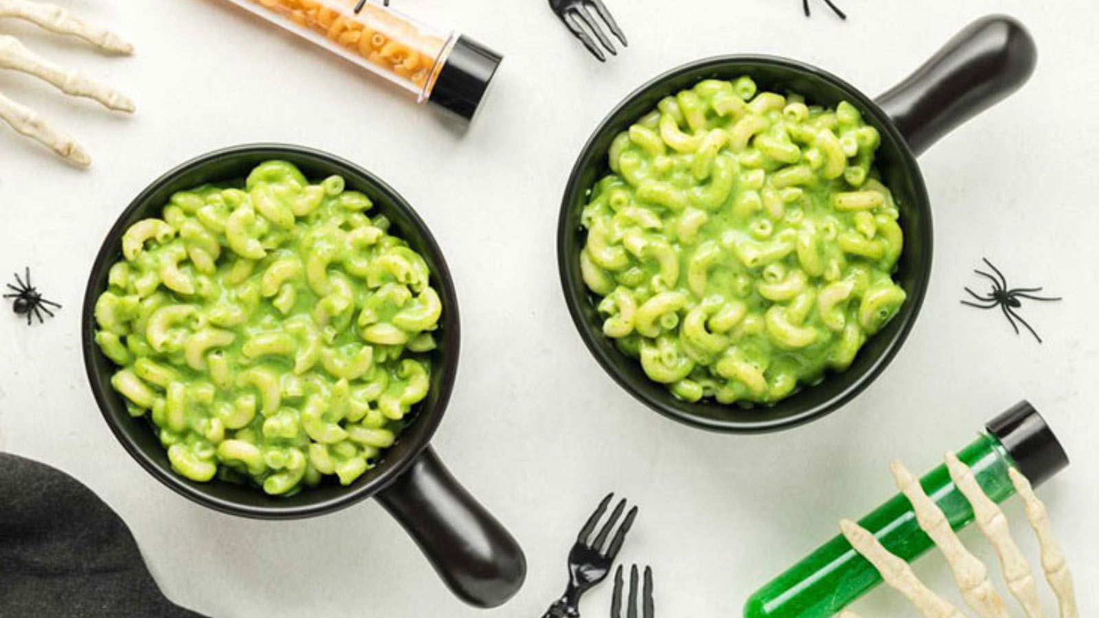 Two black bowls filled with green mac and cheese.