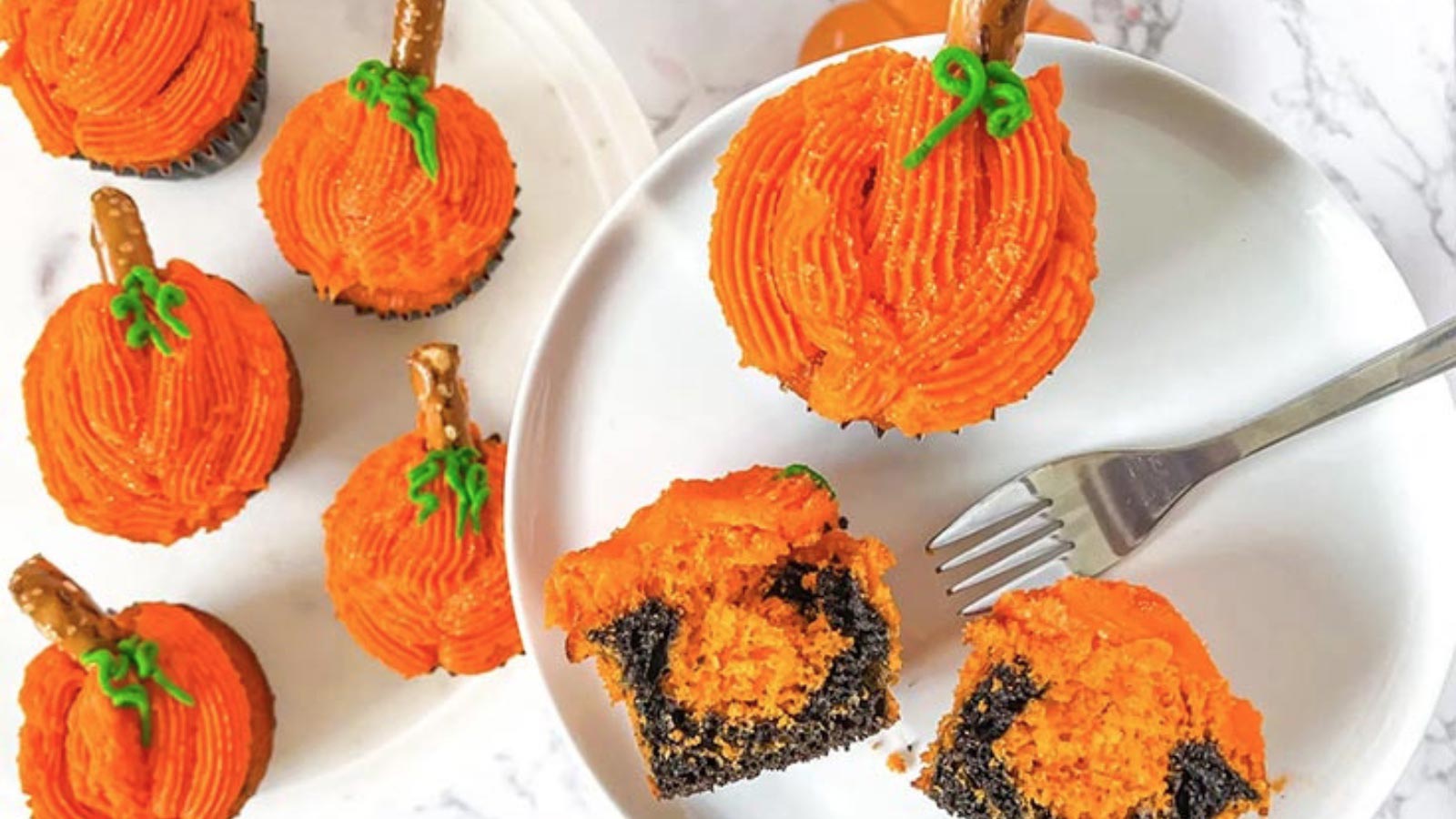 An overhead view of pumpkin cupcakes on a white plate and platter.