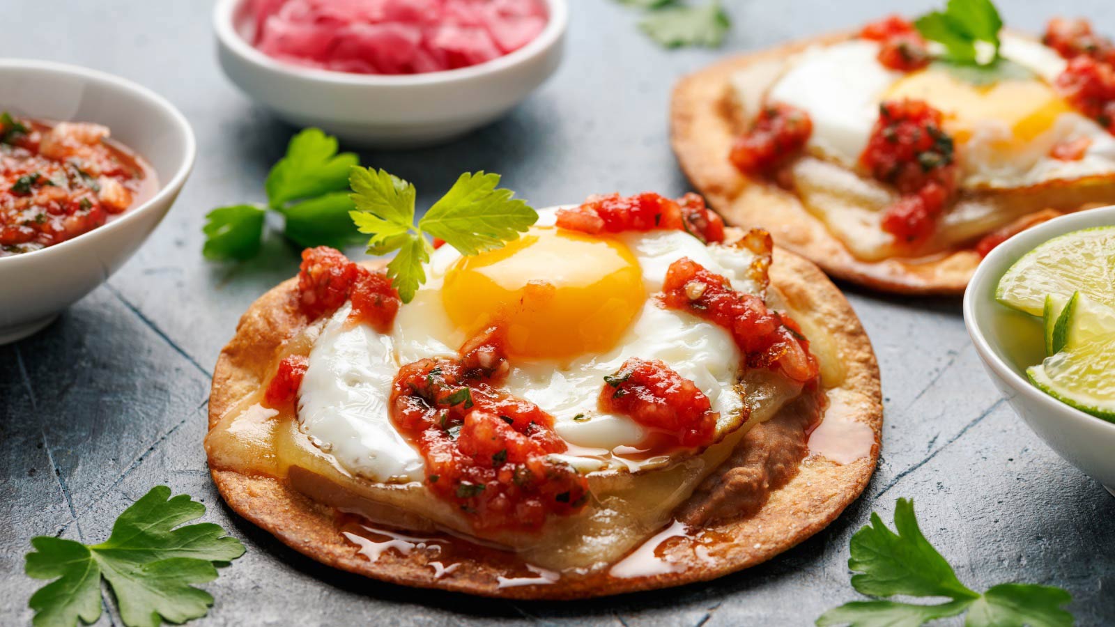Huevos Rancheros tostadas with fried egg, tomato salsa, bean paste and cheese. Mexican food.