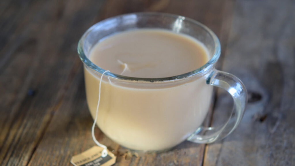 A London Fog in a glass mug on a wooden table.