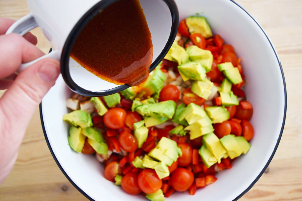 Pouring dressing over a just-made Mexican Dense Bean Salad.