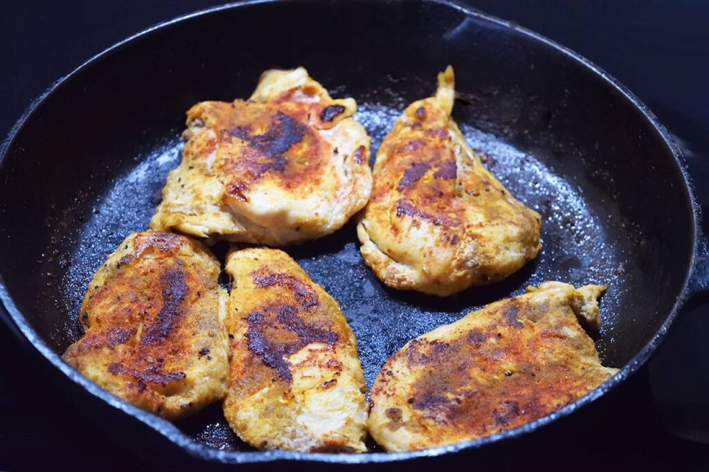 Cooked chicken breasts in a cast iron skillet.
