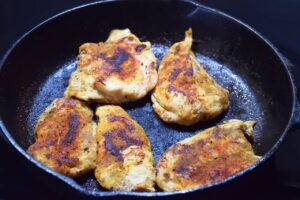 Cooked chicken breasts in a cast iron skillet.