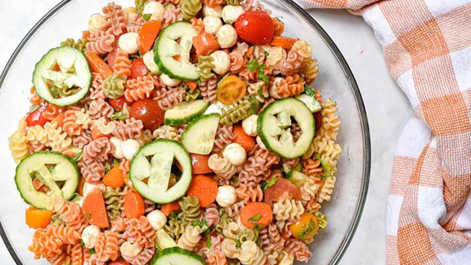 A plate of pasta with cucumber sliced to have pumpkin faces in them.