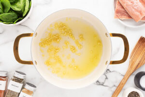 Garlic sautéing in olive oil in a pot.