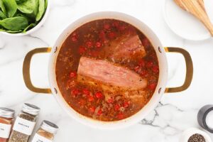 Salmon filets added to a pot of broth, tomatoes, and garlic.
