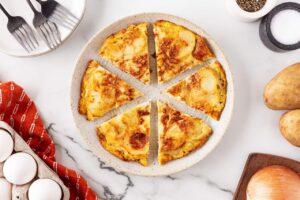 A sliced Tortilla Española on a white, ceramic platter.