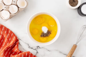 Eggs, salt, and pepper in a mixing bowl.