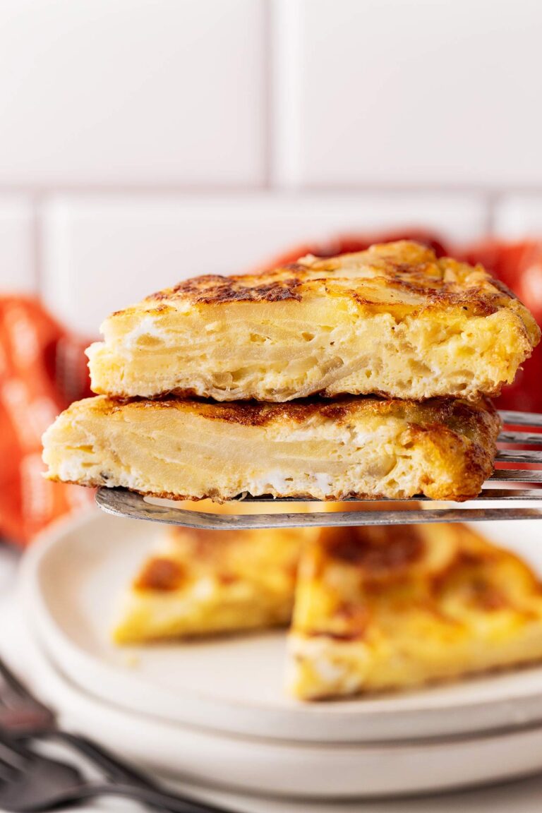 A spatula holds two, stacked slices of Tortilla Española.