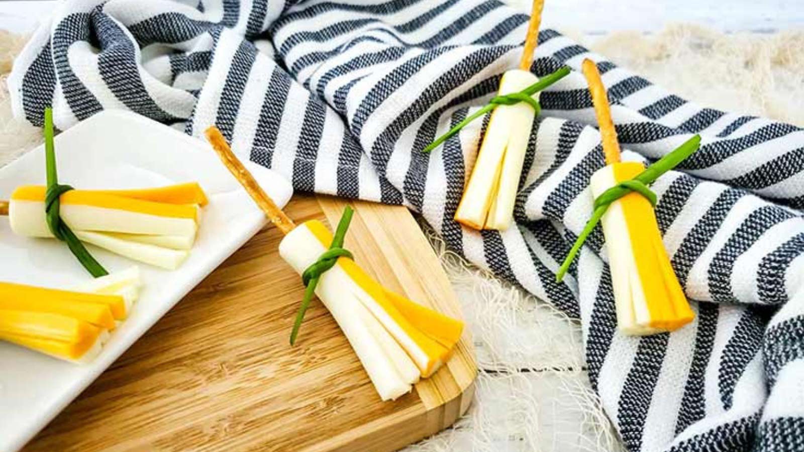 Several witches broom snacks laying on a cutting board and kitchen towel.