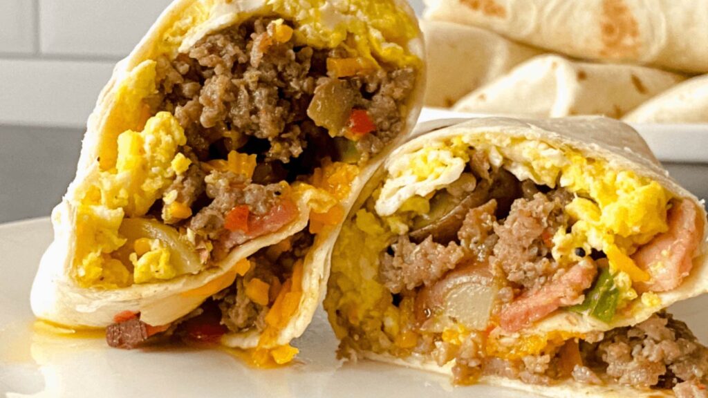 Closeup of a cut breakfast burrito. The two cut sides facing forwards next to each other.