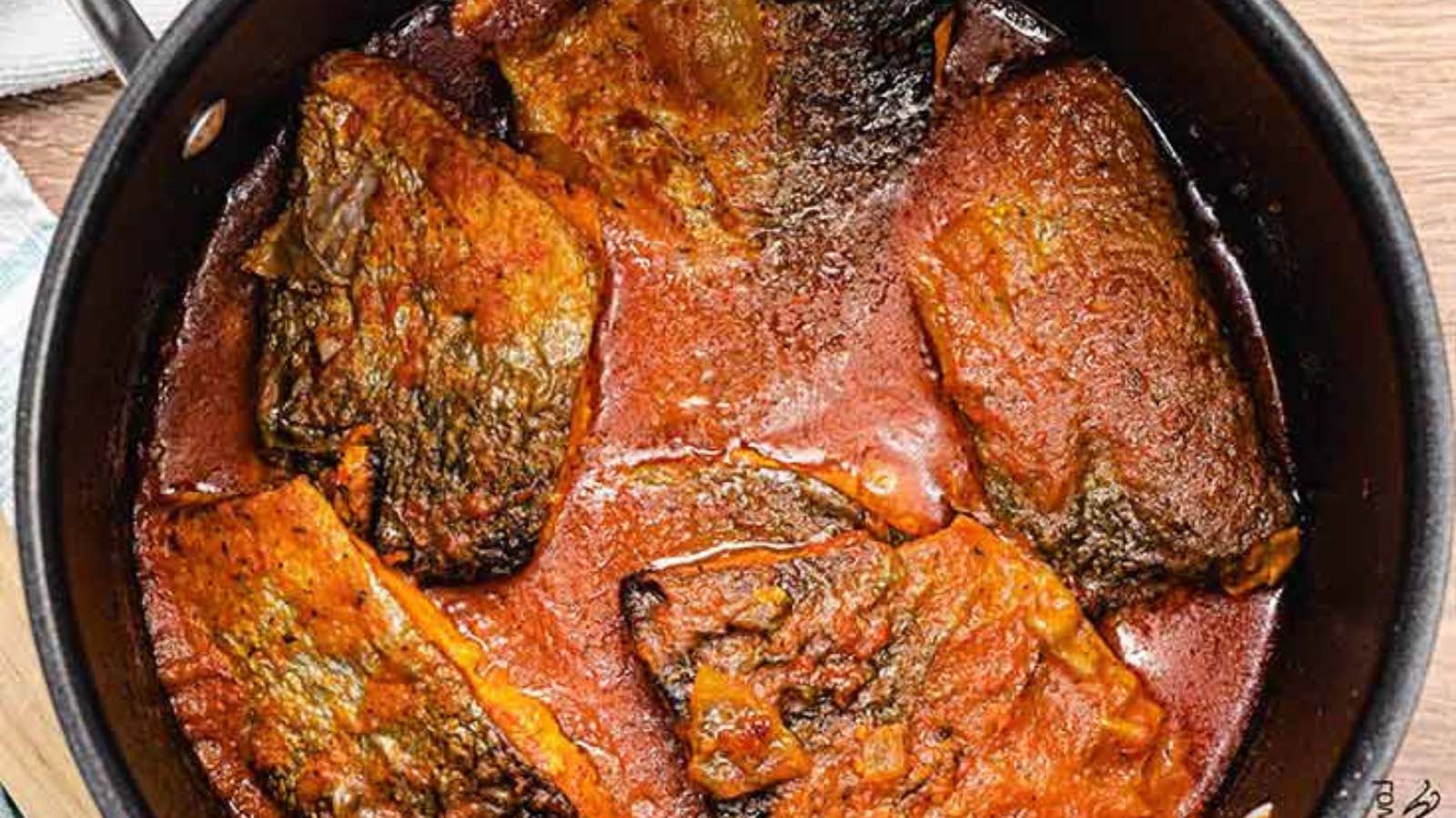 A black pot filled halfway with salmon stew.