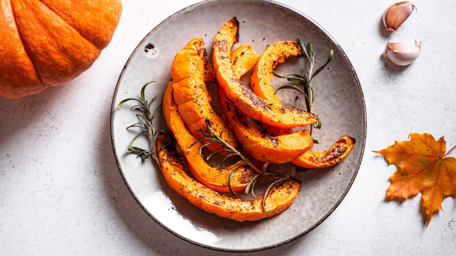 Roasted pumpkin slices with garlic and herbs. Oven baked pumpkin, seasonal autumn side dish or vegan meal.