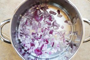 Chopped red onions in a pot with oil.