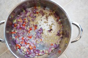 Onions, binger and red chilis sautéing in a pot.