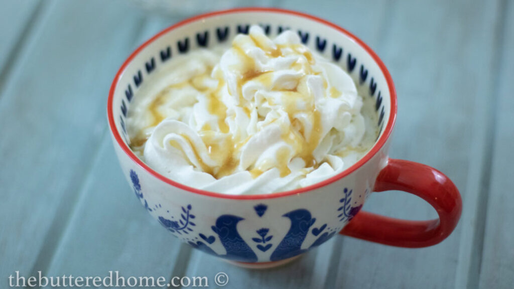 A mug filled with caramel machiato and topped with whipped cream.